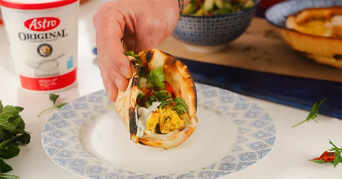 Man holding a flatbread wrap with a tub of Astro 6% yogurt in the background