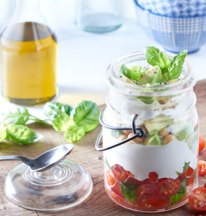 Savoury Greek Parfait made with Astro Yogurt in a mason jar on a wooden table with basil leaves adn olive oil in the background.